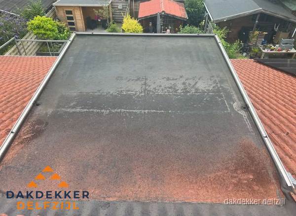 Verouderd plat dak met slijtage tussen schuine daken in Delfzijl Verouderd plat dak met slijtage tussen schuine daken in Delfzijl