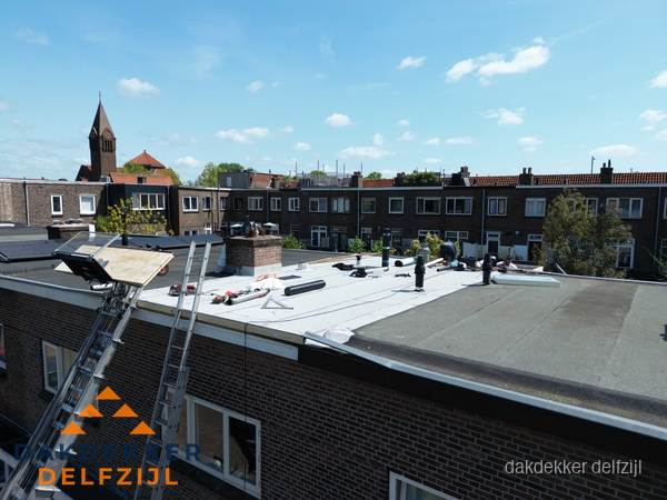 Dakdekkers aan het werk op plat dak in Delfzijl