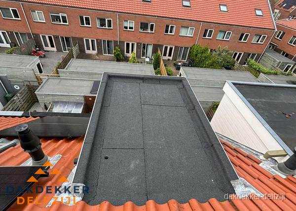 Plat dak met bitumen bedekking naast dakkapel in Delfzijl