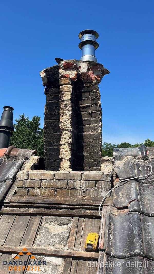 Beschadigde schoorsteen met nieuwe rookgasafvoer op oud dak in Delfzijl Beschadigde schoorsteen met nieuwe rookgasafvoer op oud dak in Delfzijl