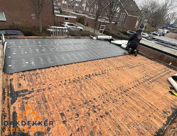 Dakdekker legt onderlaag op plat dak met houten constructie in Delfzijl