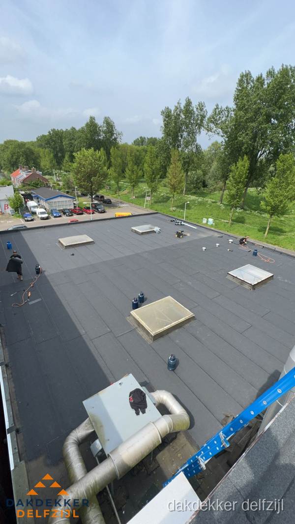 Dakdekker aan het werk op groot plat dak met bitumen in Delfzijl Dakdekker aan het werk op groot plat dak met bitumen in Delfzijl