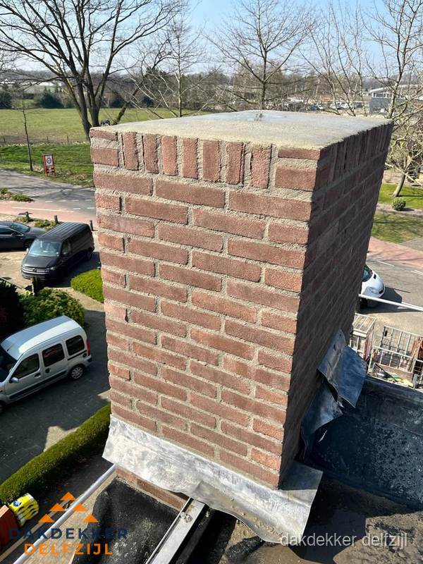 Gemetselde schoorsteen met loodaansluiting op dak in Delfzijl Gemetselde schoorsteen met loodaansluiting op dak in Delfzijl